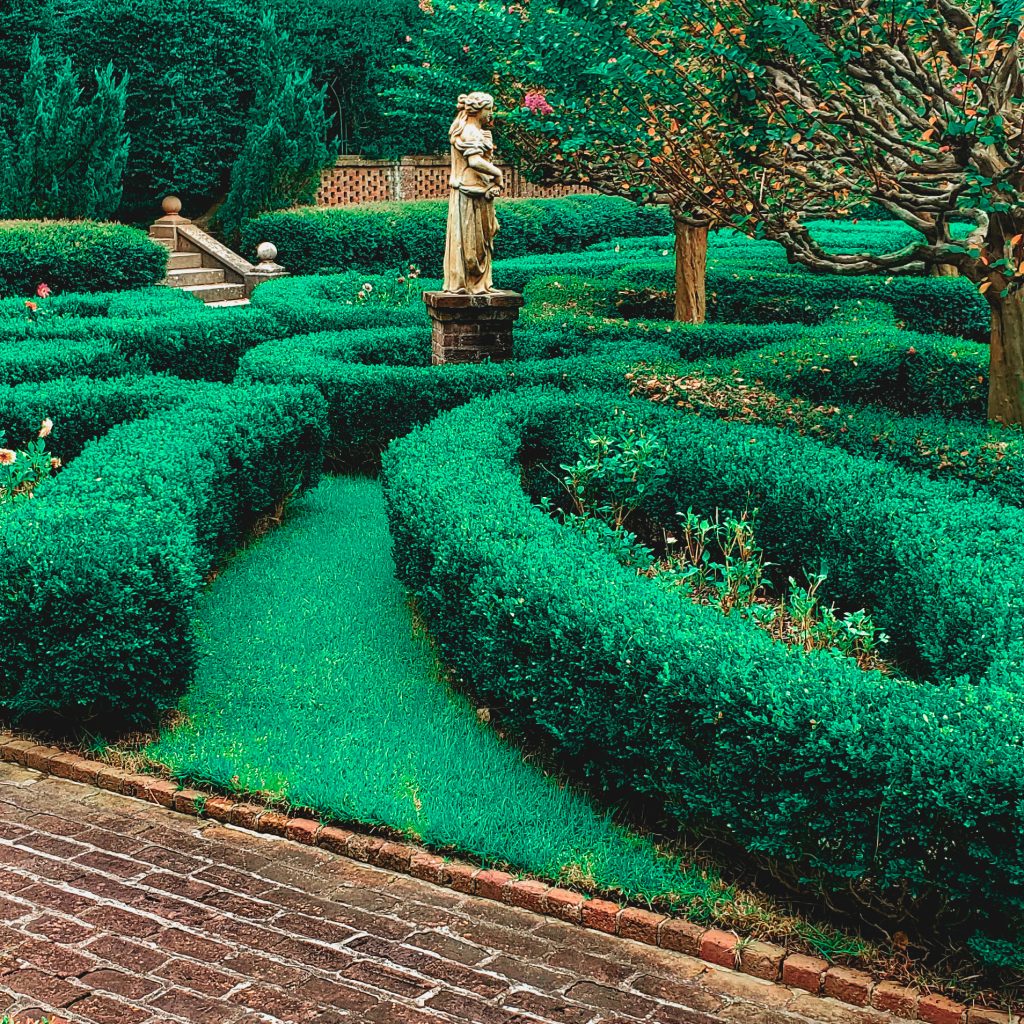 green garden with manicured bushes and a statue of a woman