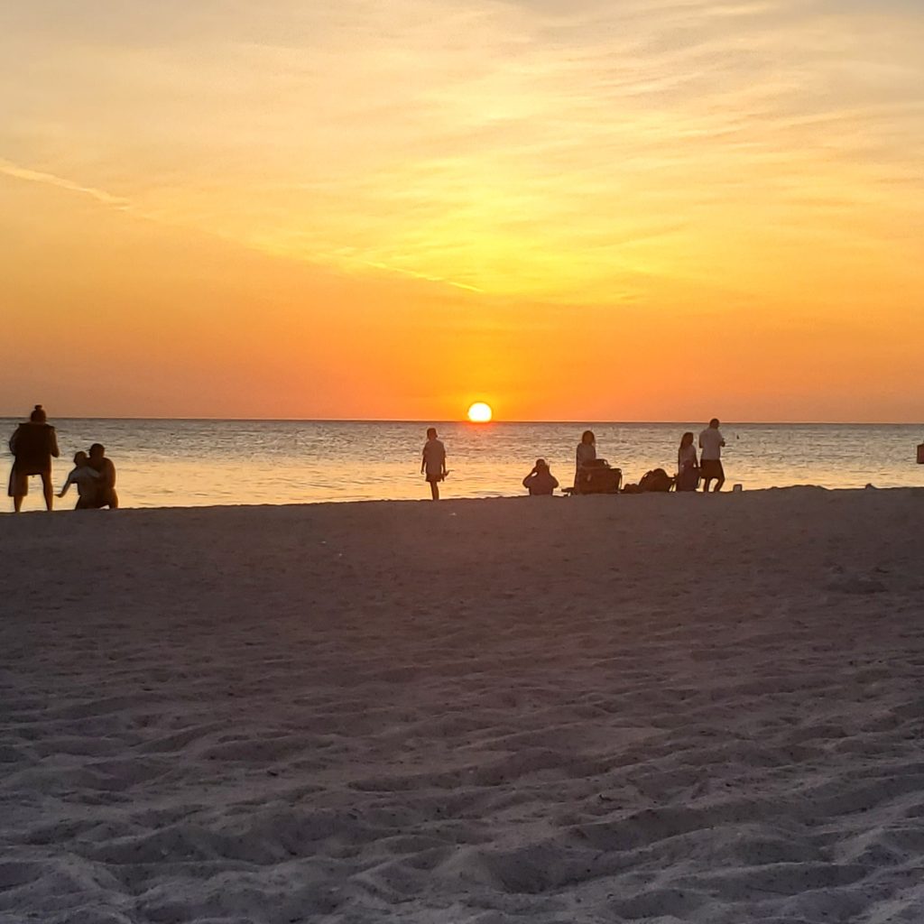 Sunset in Anna Maria Island with people sitting on the sand