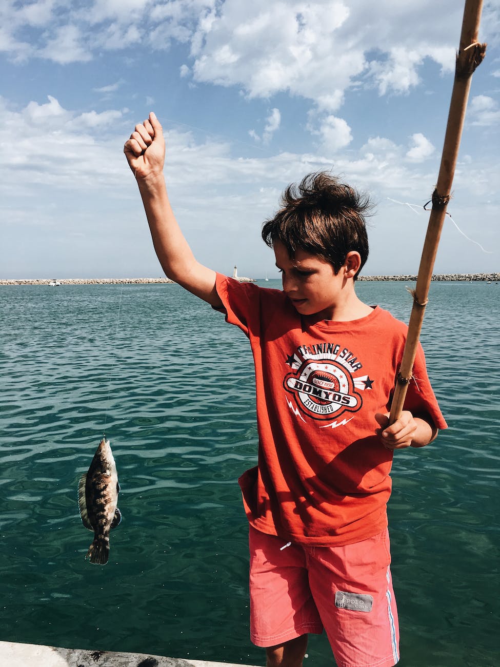 boy catching fish with fishing rod