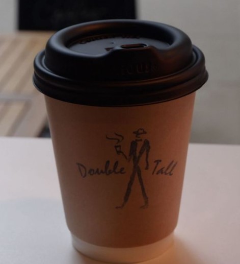 a paper cup of coffee in a shibuya cafe with double tall logo