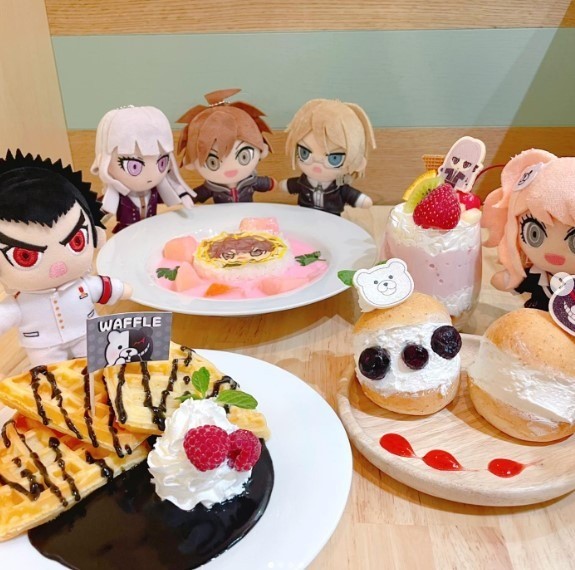 anime plushies next to waffles and other sweets at an anime cafe in tokyo