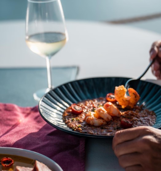 person eating fried shrimp with white wine at santorini restaurant