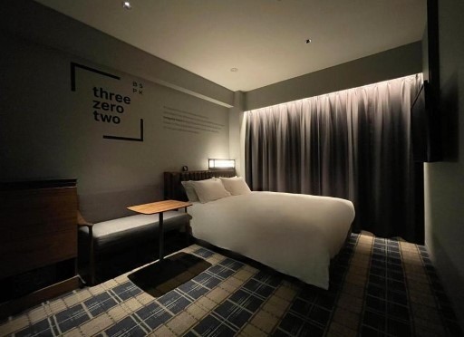a dark hotel room in tokyo with striped carpet and a full bed