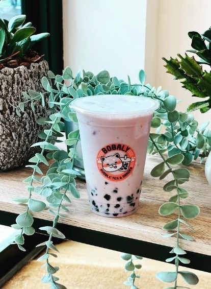 pink bubble tea surrounded by plants