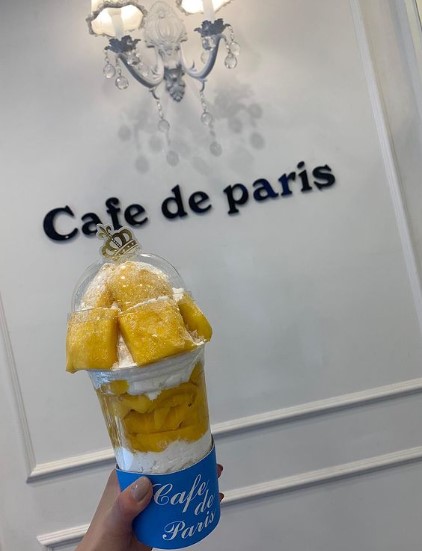 mango flavored drink with cafe de paris brand in background with fancy lights