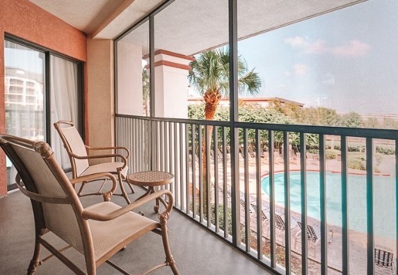  orange and pink screened in balcony with pool view and palm tree