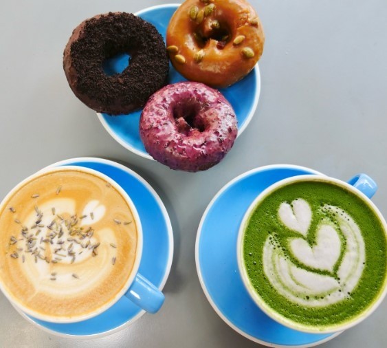 two lattes with art and three donuts on a plate