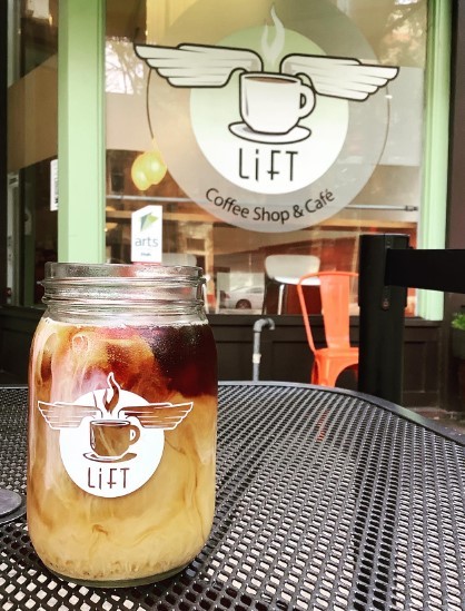 lift iced coffee on table in front of cafe