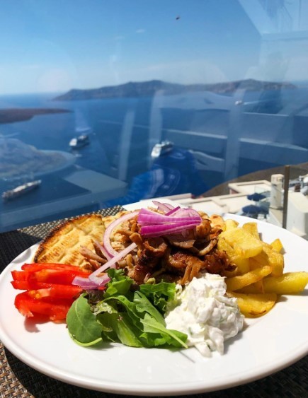pork gyro plate with the view of the caldera in santorini