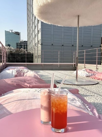 pink pillows on rooftop in seoul cafe with two iced beverages