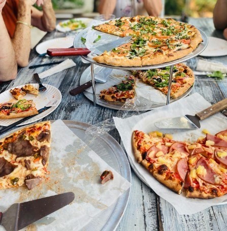a table full of different types of pizza with people