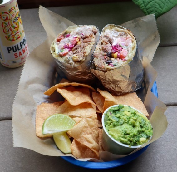 beef burrito with guac and chips in a basket
