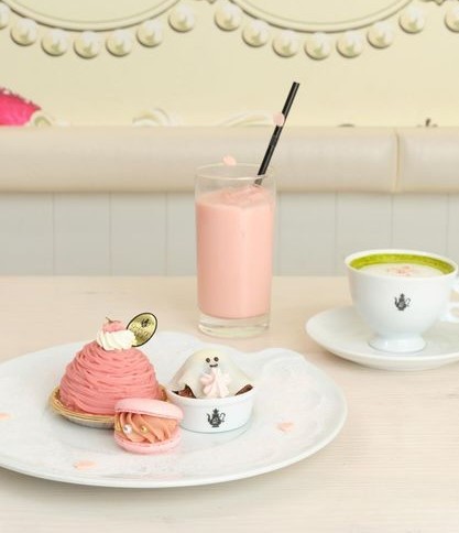 a tall pink drink with adorable pink pastries on a plate