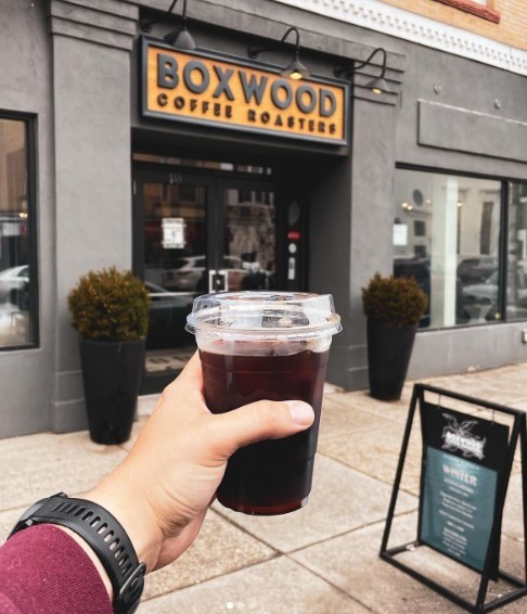 man holding coffee in front of boxwood coffee entrance in new jersey