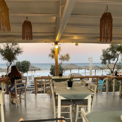 outdoor seating restaurant on kamari beach with brown light fixtures and white tables