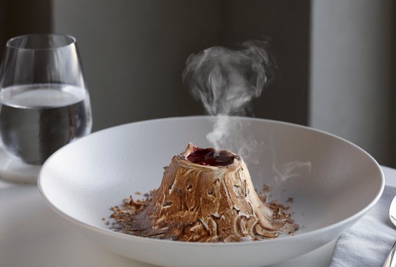 volcano dessert inside a white bowl with a glass of water at a romantic santorini restaurant
