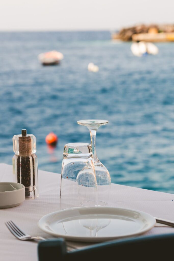 two empty glasses faced down on table with water in background in santorini