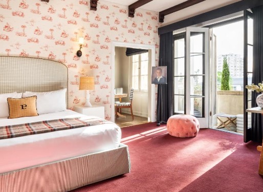 a charming hotel room with a balcony drenched in light and dark pink