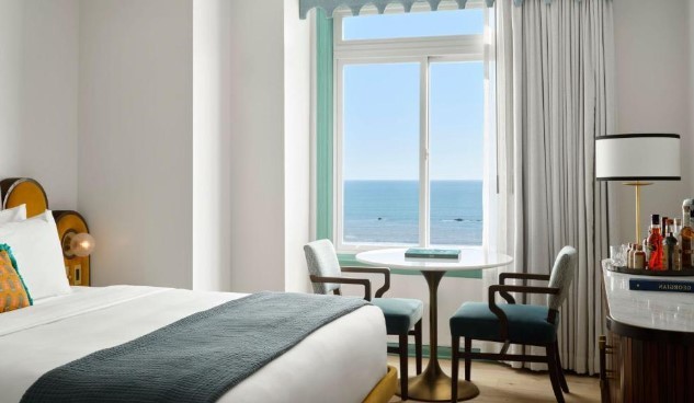 full size bed with chairs and a desk overlooking the pacific ocean