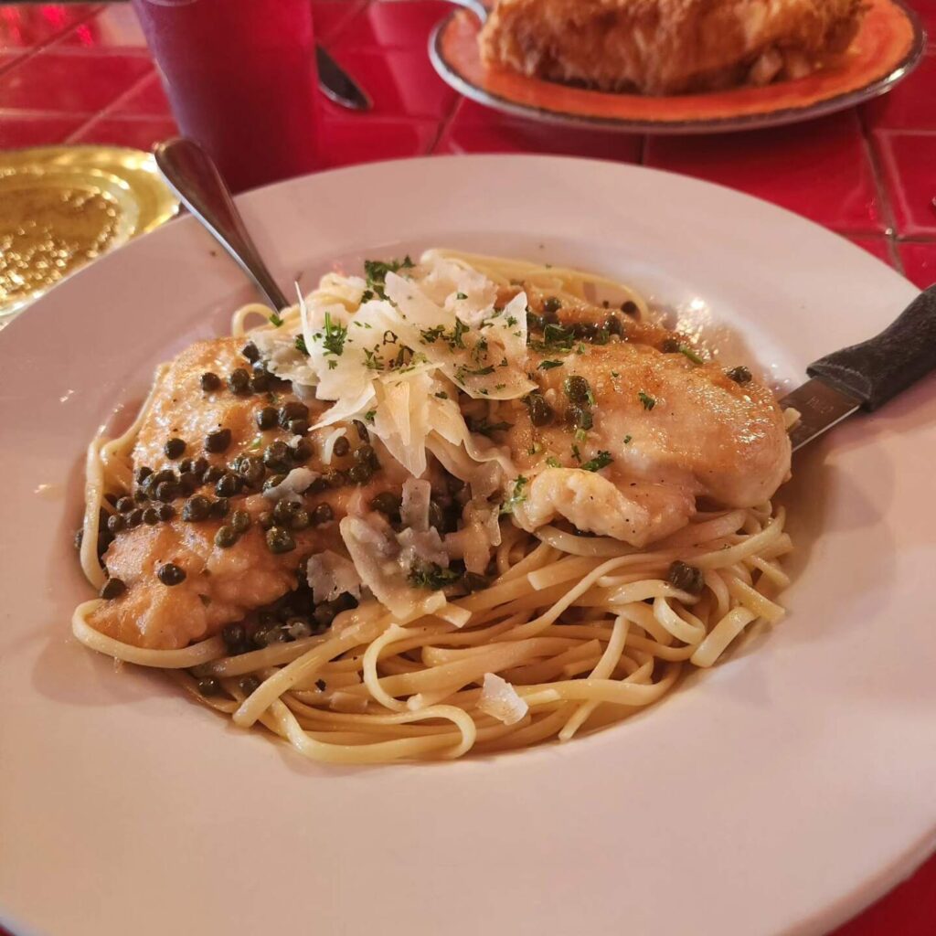chicken on top of pasta with a white wine sauce