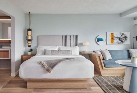 a cozy bed with a hanging light fixture and a minimalistic sofa and table at santa monica boutique hotel